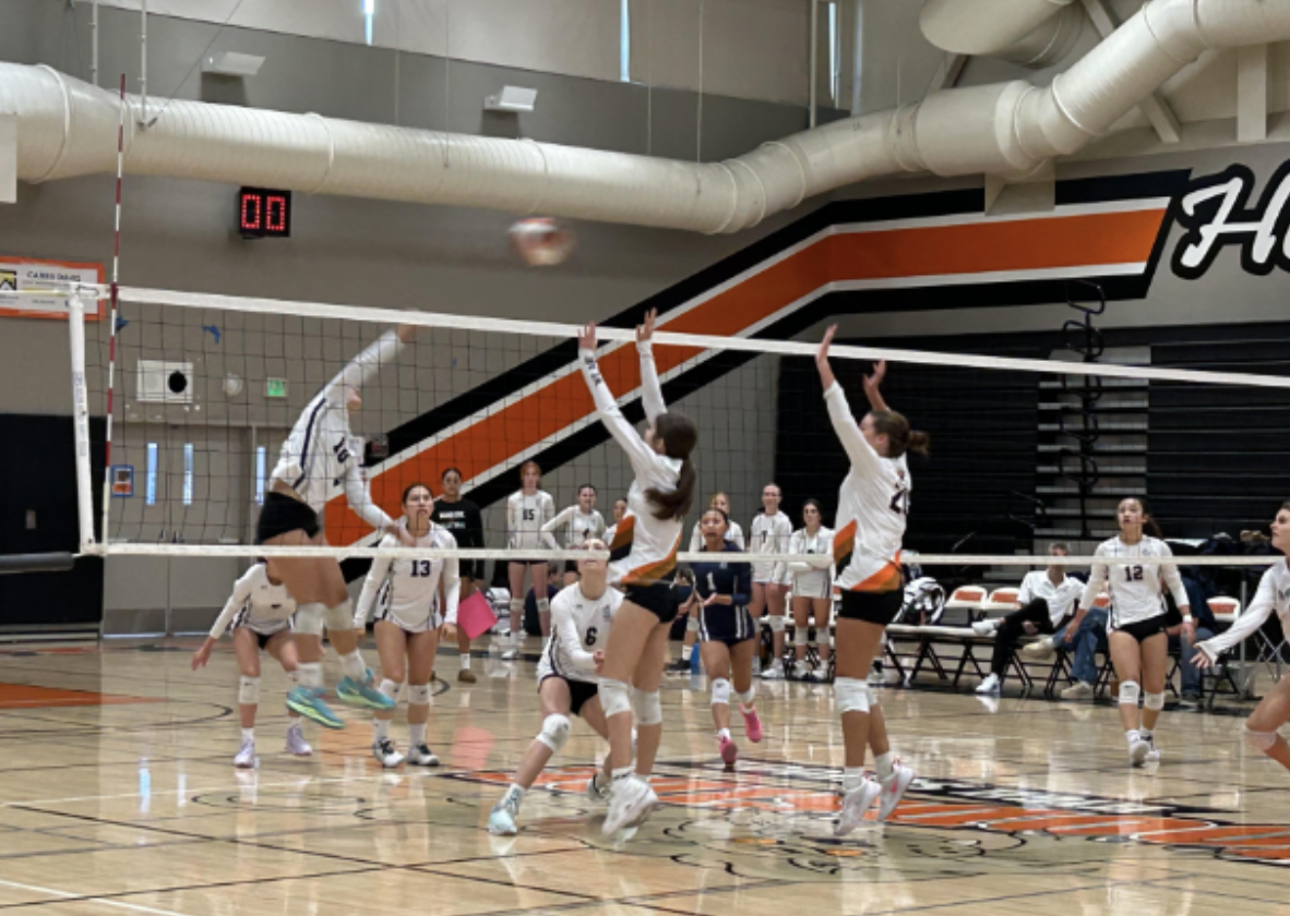 Girls JV volleyball players block a ball against Carlmont during their match last Thursday.